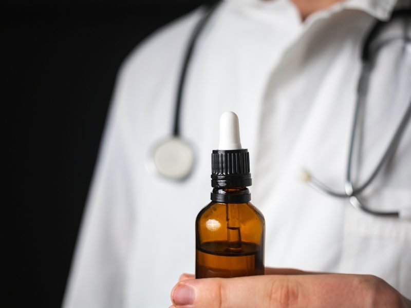 Doctor hands opening a glass pipette CBD oil bottle