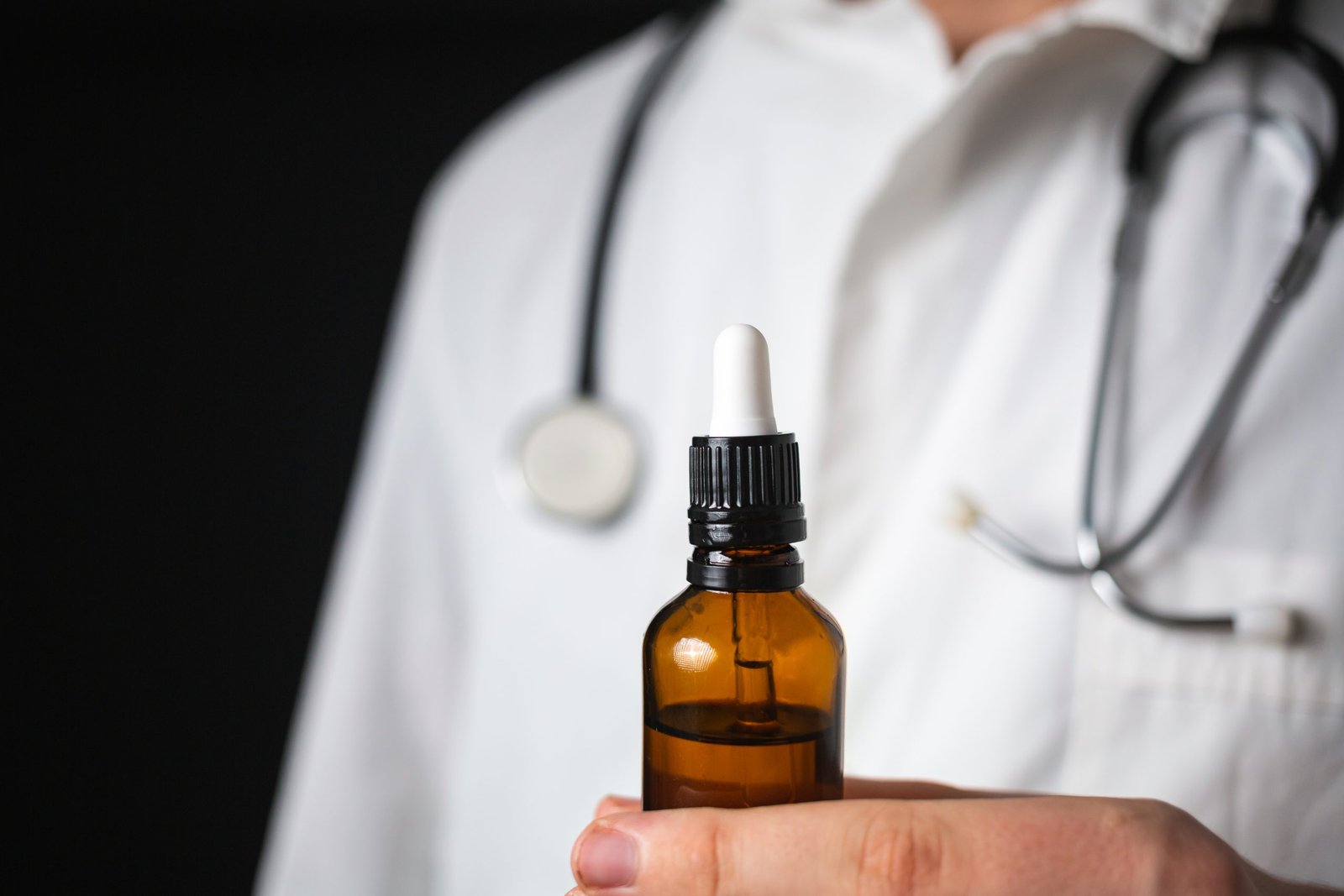 Doctor hands opening a glass pipette CBD oil bottle